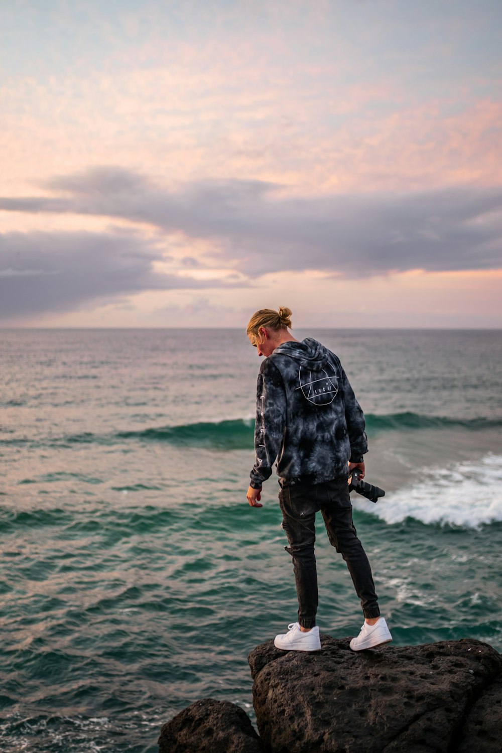 man in black and white jacket standing on sea shore during daytime