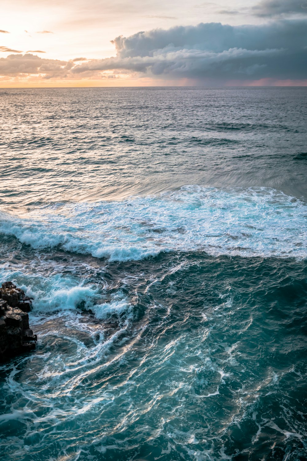 Les vagues de l’océan s’écrasent sur la formation de roches noires pendant la journée