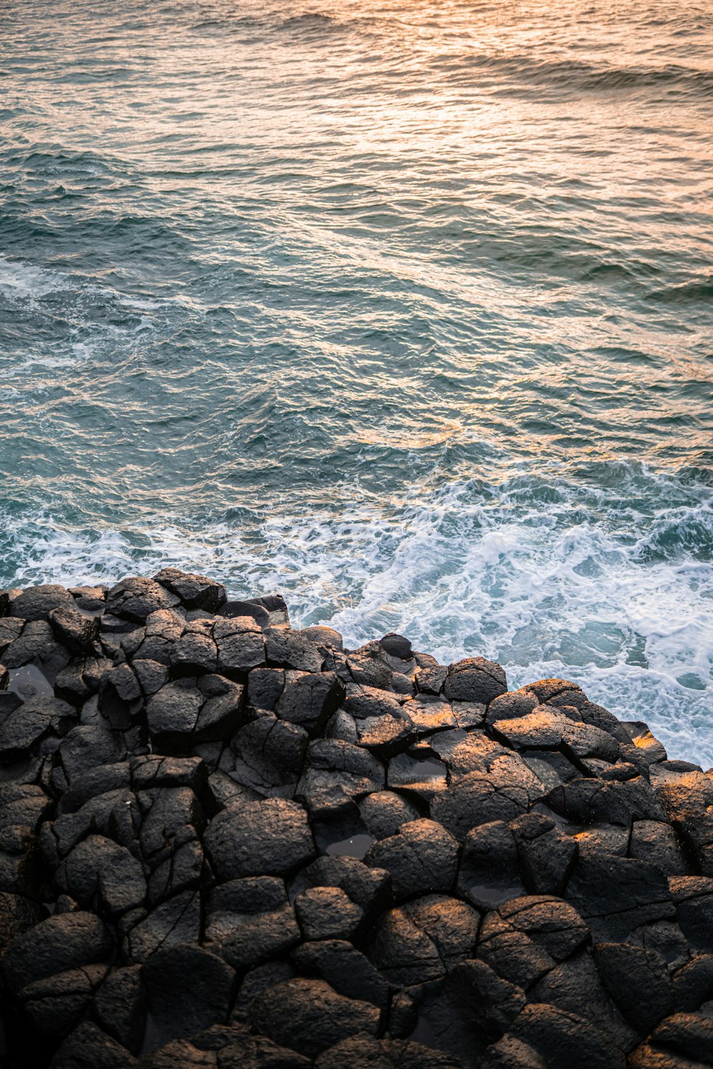 rochas marrons ao lado do corpo de água durante o dia