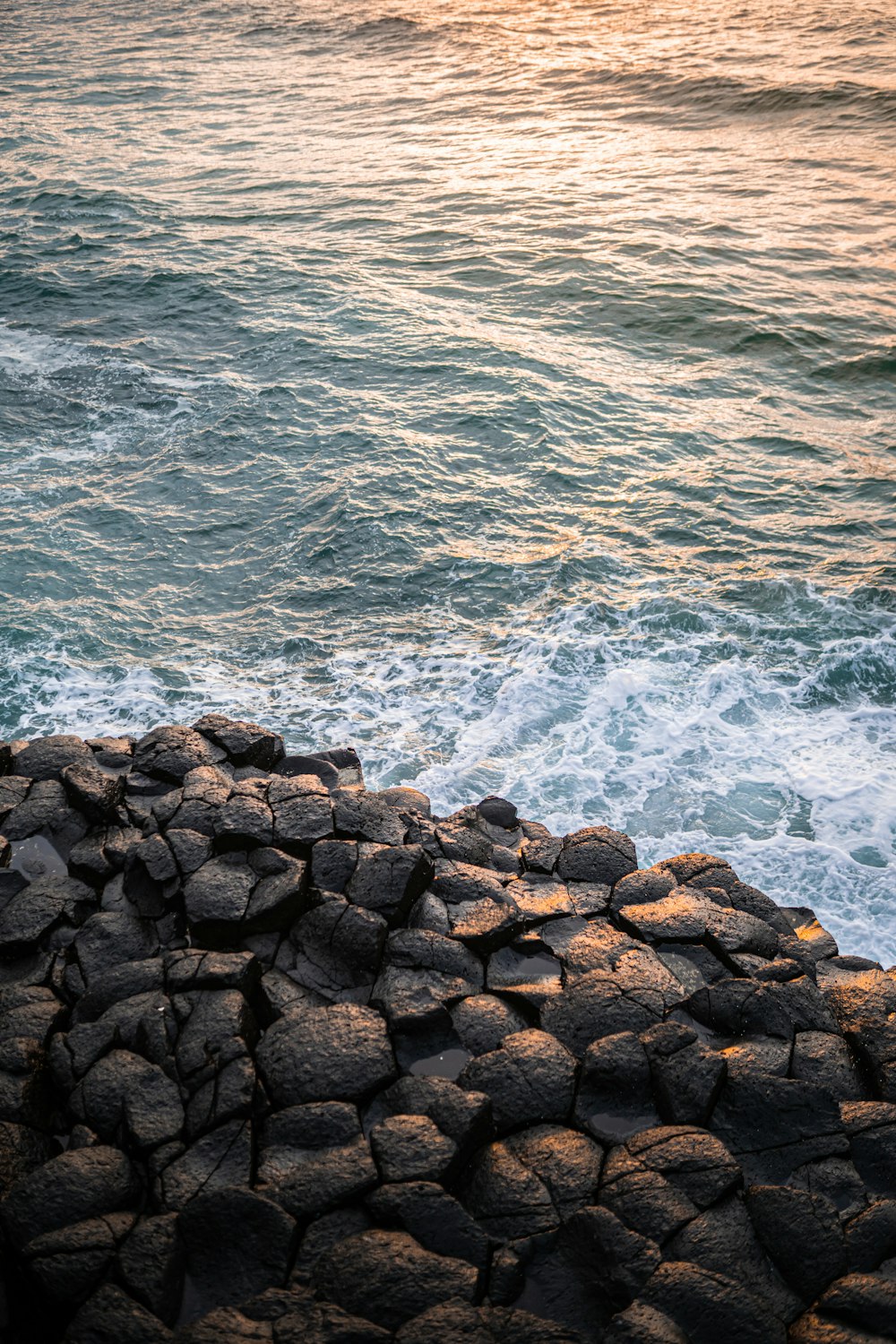 brown rocks beside body of water during daytime