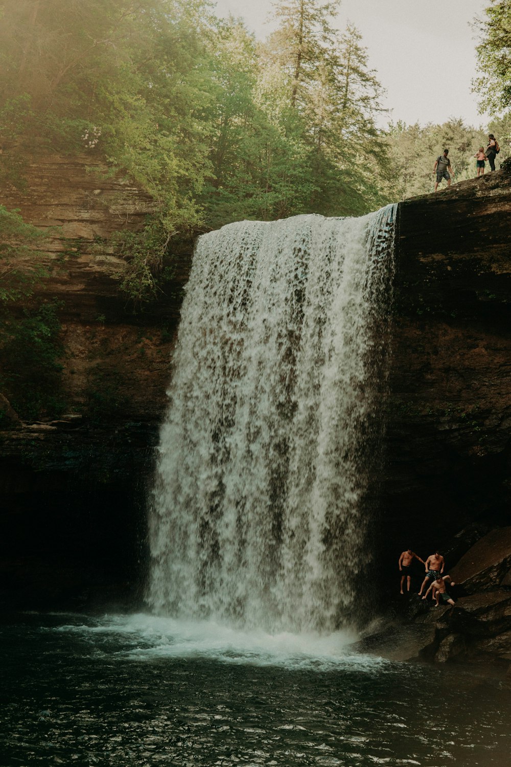 man in red shirt standing in front of waterfalls during daytime