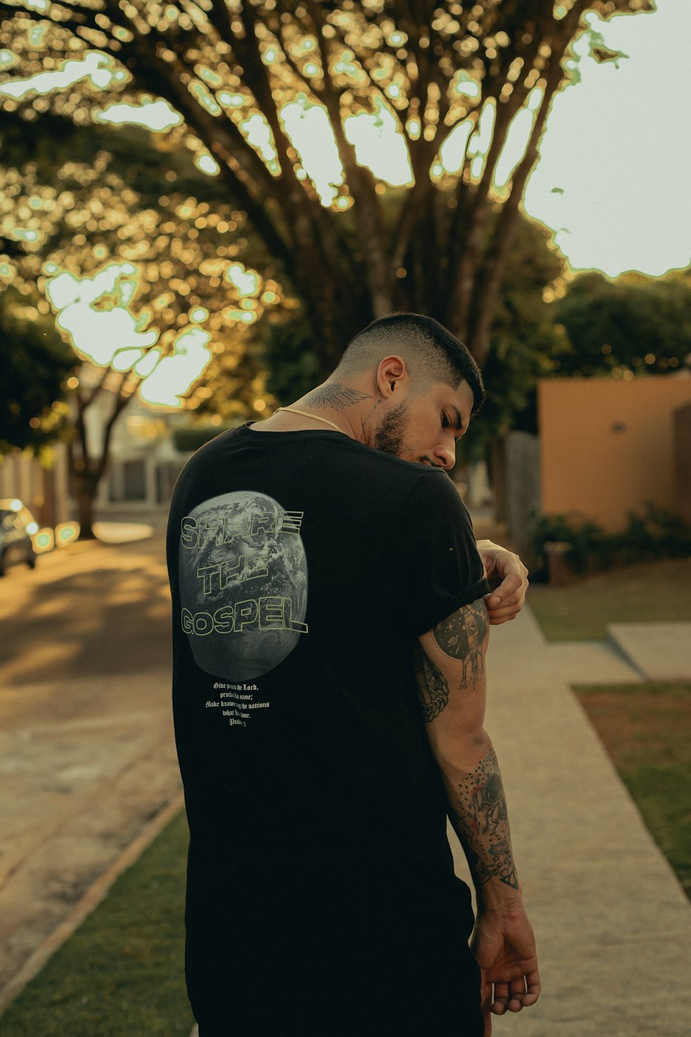 man in black t-shirt standing on sidewalk during daytime