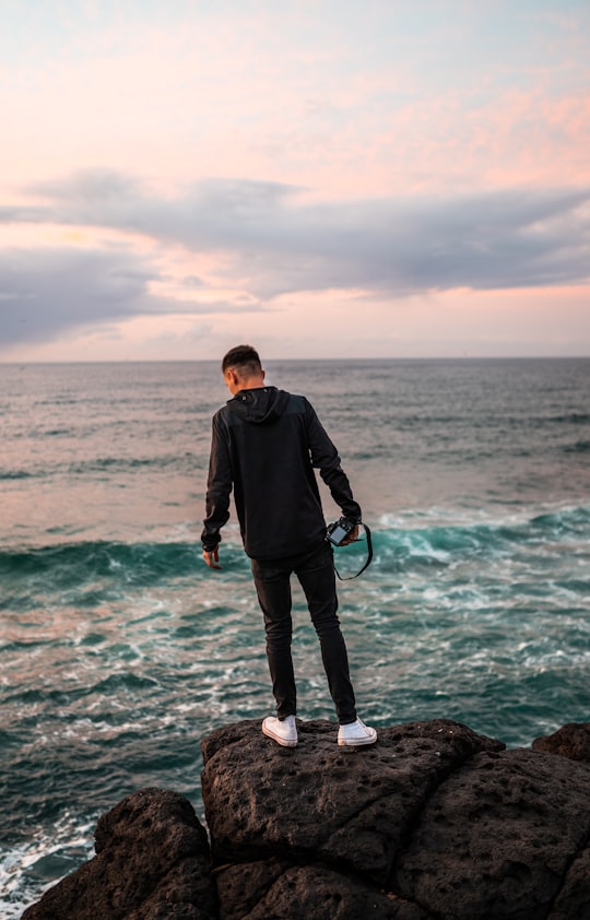 man in black jacket standing on rock near sea during daytime in Fingal Head Australia