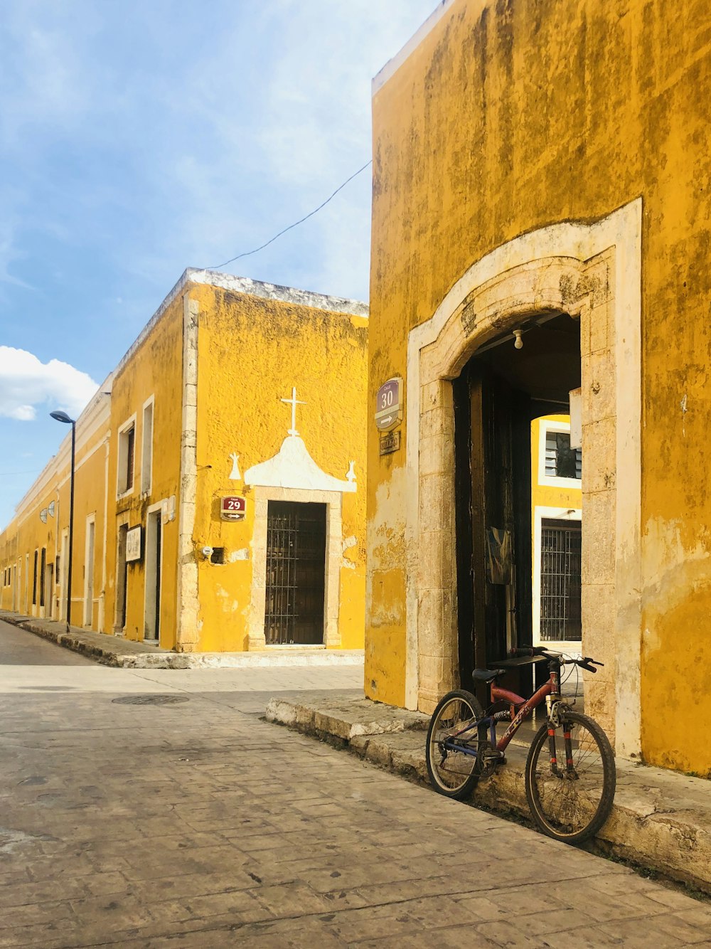 Bicicleta roja estacionada junto a un edificio de concreto amarillo durante el día