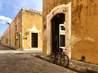 red bicycle parked beside brown concrete building during daytime