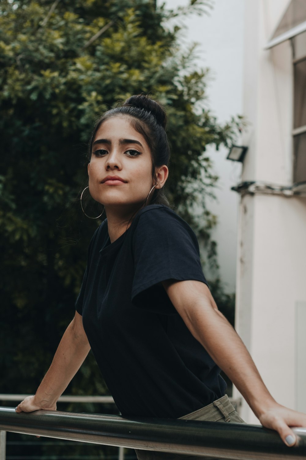 woman in black crew neck t-shirt standing near green tree during daytime