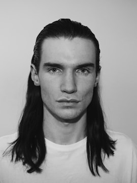 Black and white portrait of a transgender individual looking confidently into the camera.