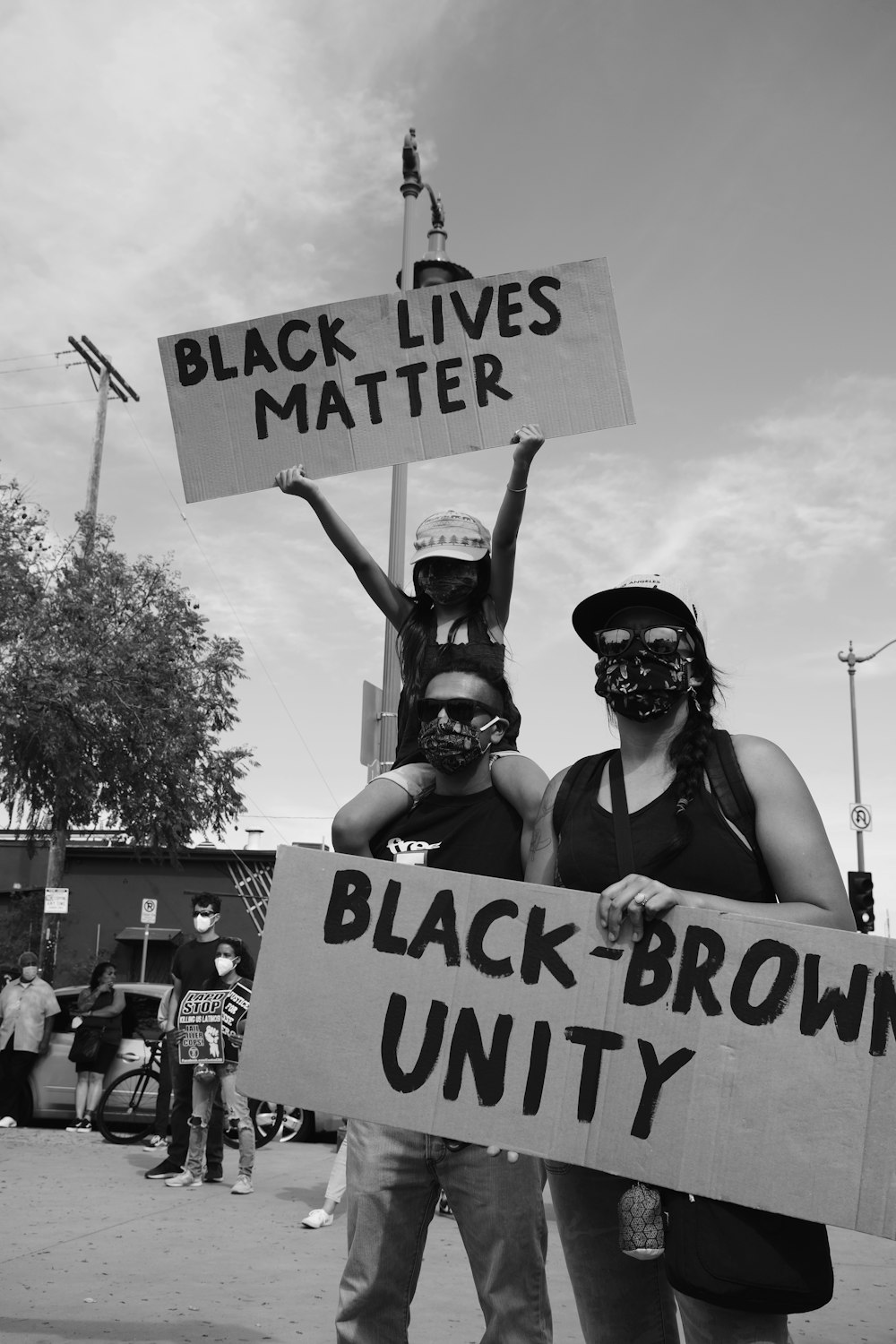 a group of people holding signs and wearing masks