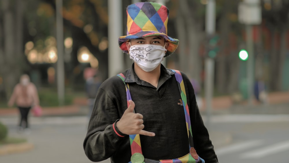 man in black jacket wearing multi color hat