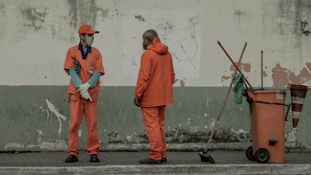 man in orange long sleeve shirt and red pants holding stick