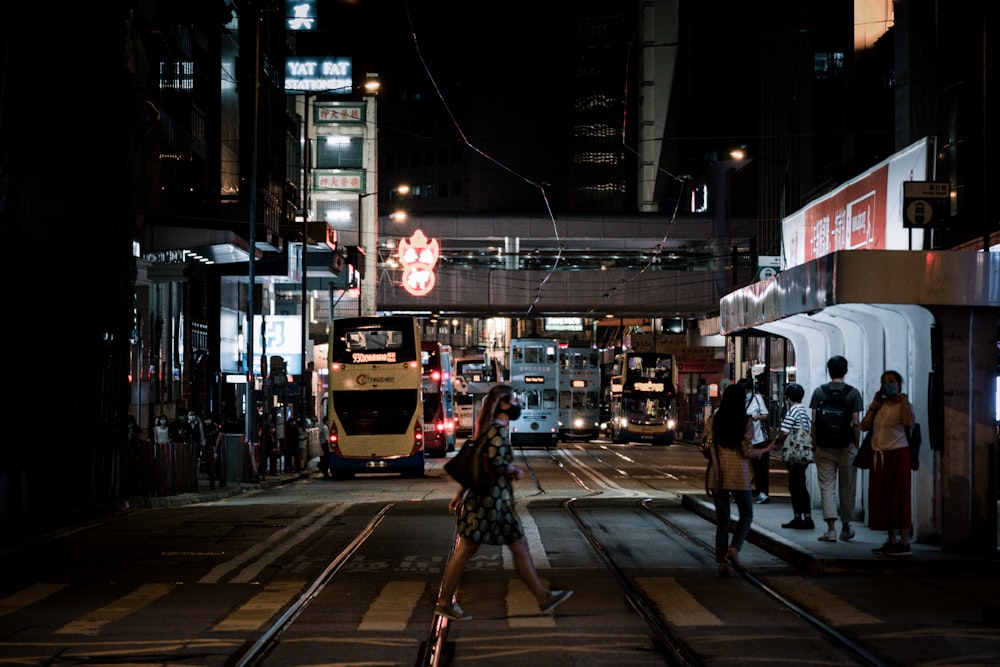 Frau in schwarz-weißem Kleid geht nachts auf dem Bürgersteig spazieren