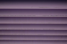 Several purple PVC pipes with black text printed on them. The text includes specifications and a caution that the water is not for drinking.