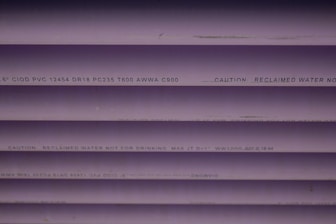Several purple PVC pipes with black text printed on them. The text includes specifications and a caution that the water is not for drinking.