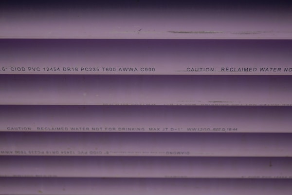 Several purple PVC pipes with black text printed on them. The text includes specifications and a caution that the water is not for drinking.