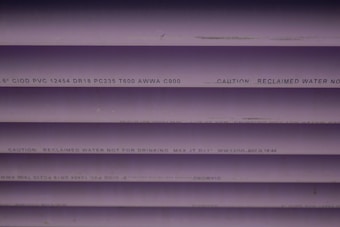Several purple PVC pipes with black text printed on them. The text includes specifications and a caution that the water is not for drinking.