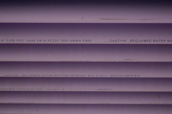 Several purple PVC pipes with black text printed on them. The text includes specifications and a caution that the water is not for drinking.