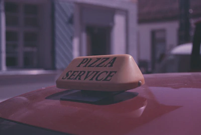 a pizza service sign on top of a red car