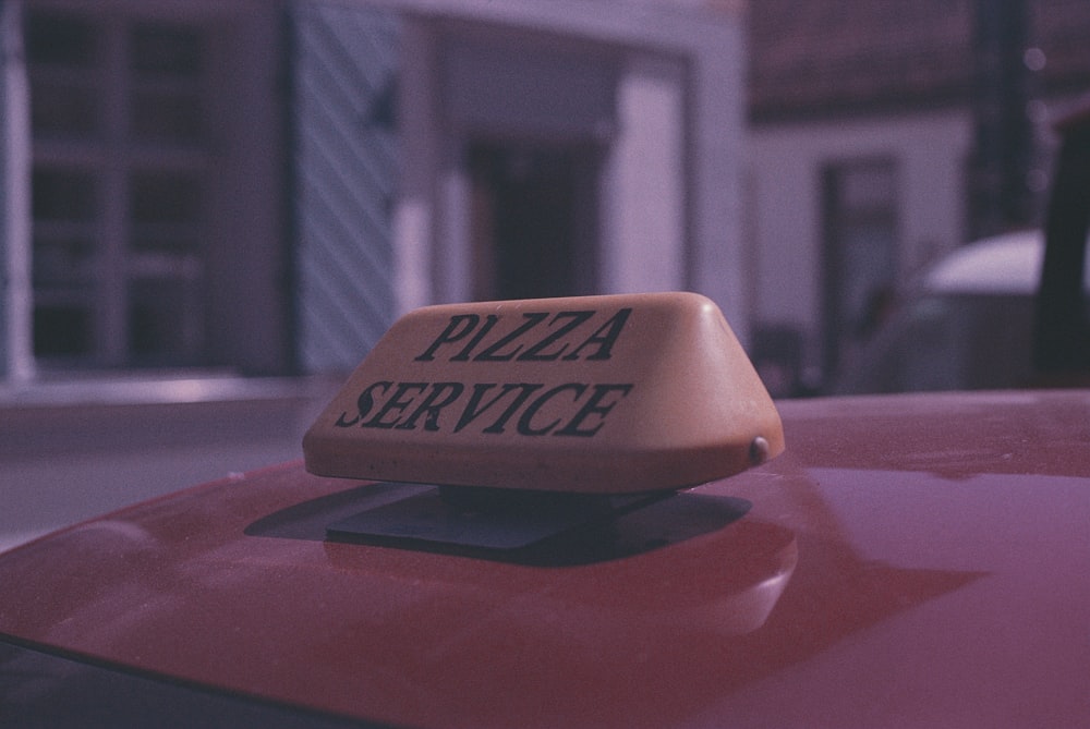 a pizza service sign on top of a red car