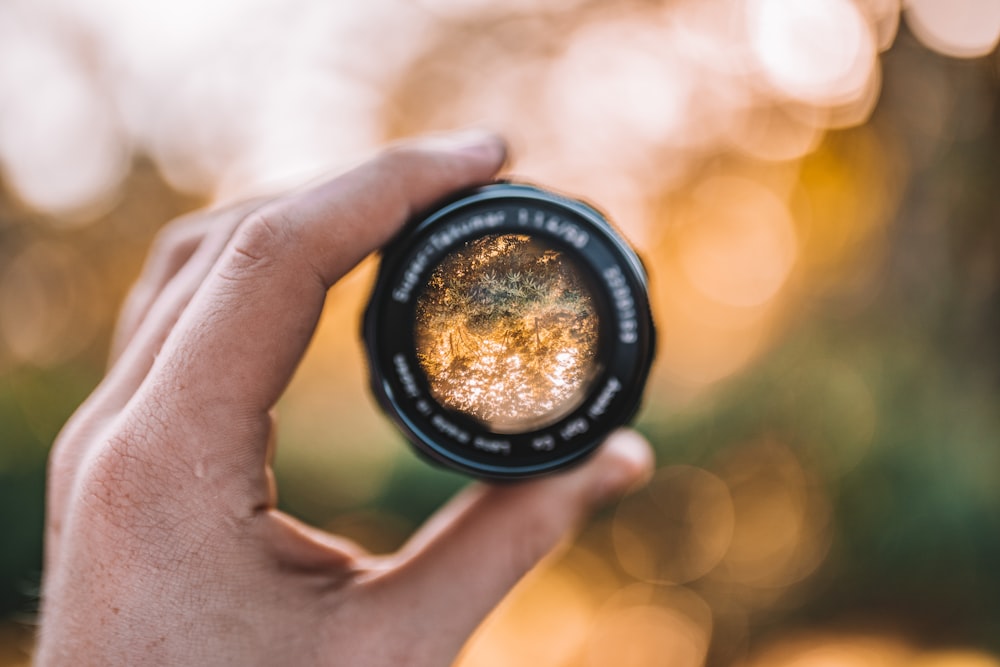 person holding black round camera lens