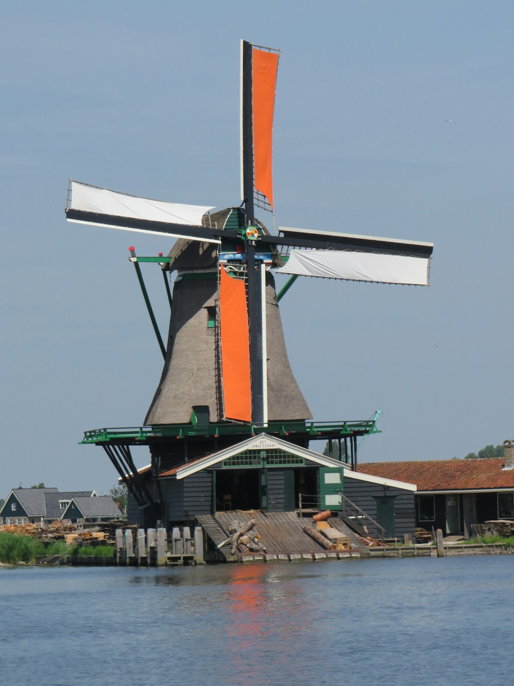 orange and white windmill near body of water during daytime