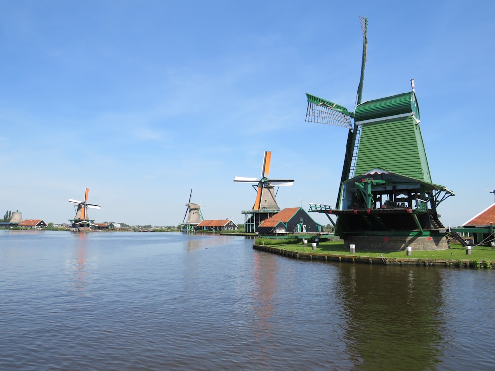 Moulin à vent vert et brun près d’un plan d’eau pendant la journée