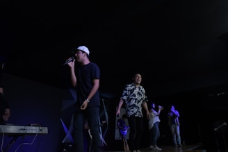 A group of diverse people singing together around a piano.