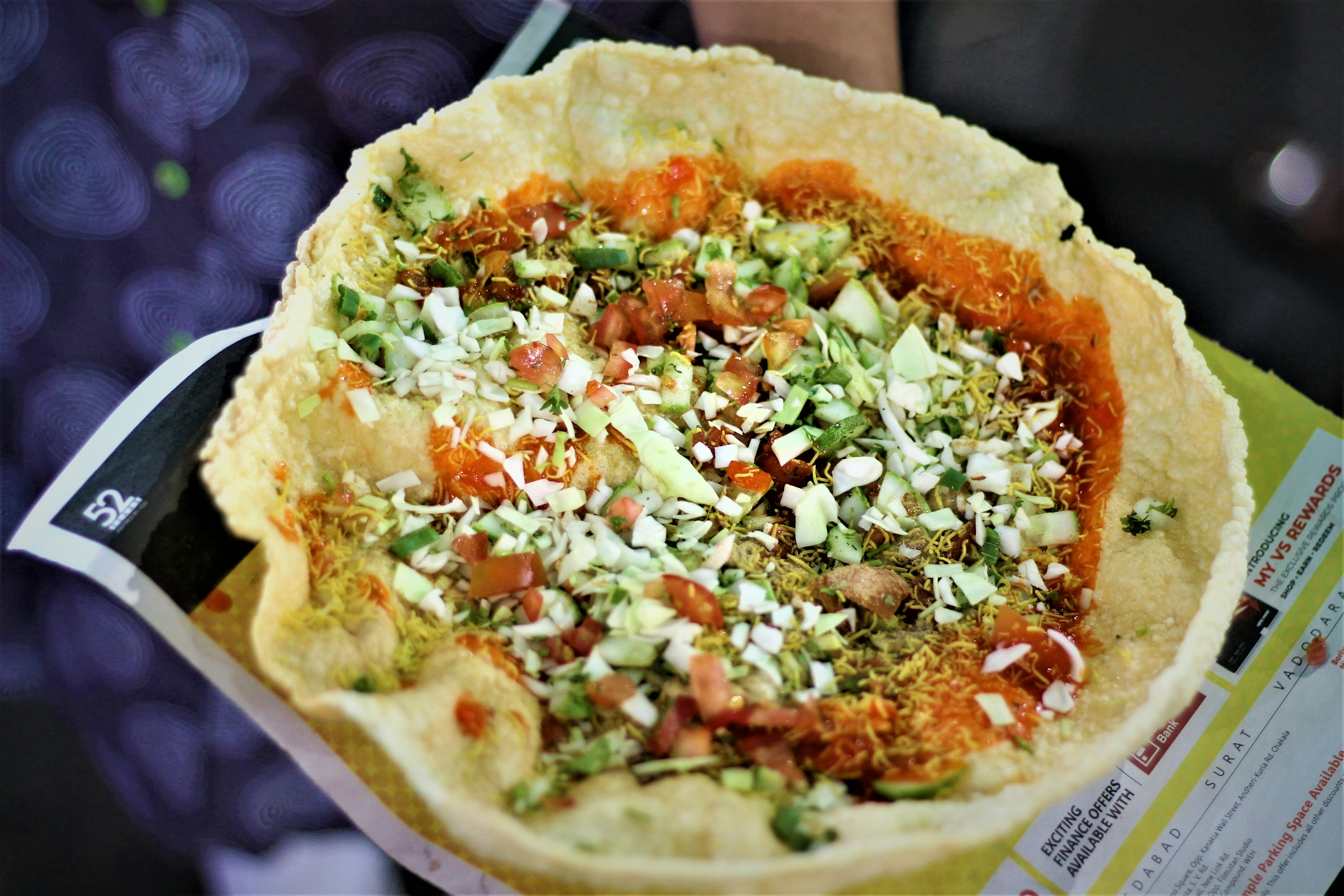 Colorful plate of spicy chaat with crispy papdi, tangy chutneys, and fresh garnishes