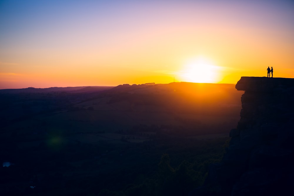 Silueta de la persona de pie en la montaña durante la puesta del sol