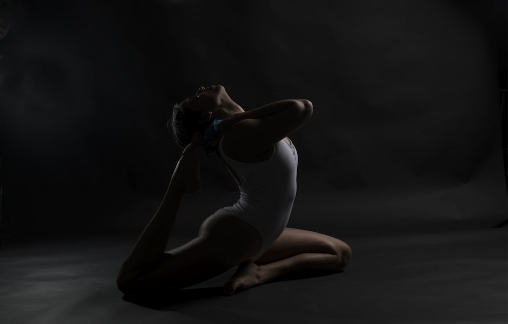 woman in white tank top and black shorts kneeling on floor