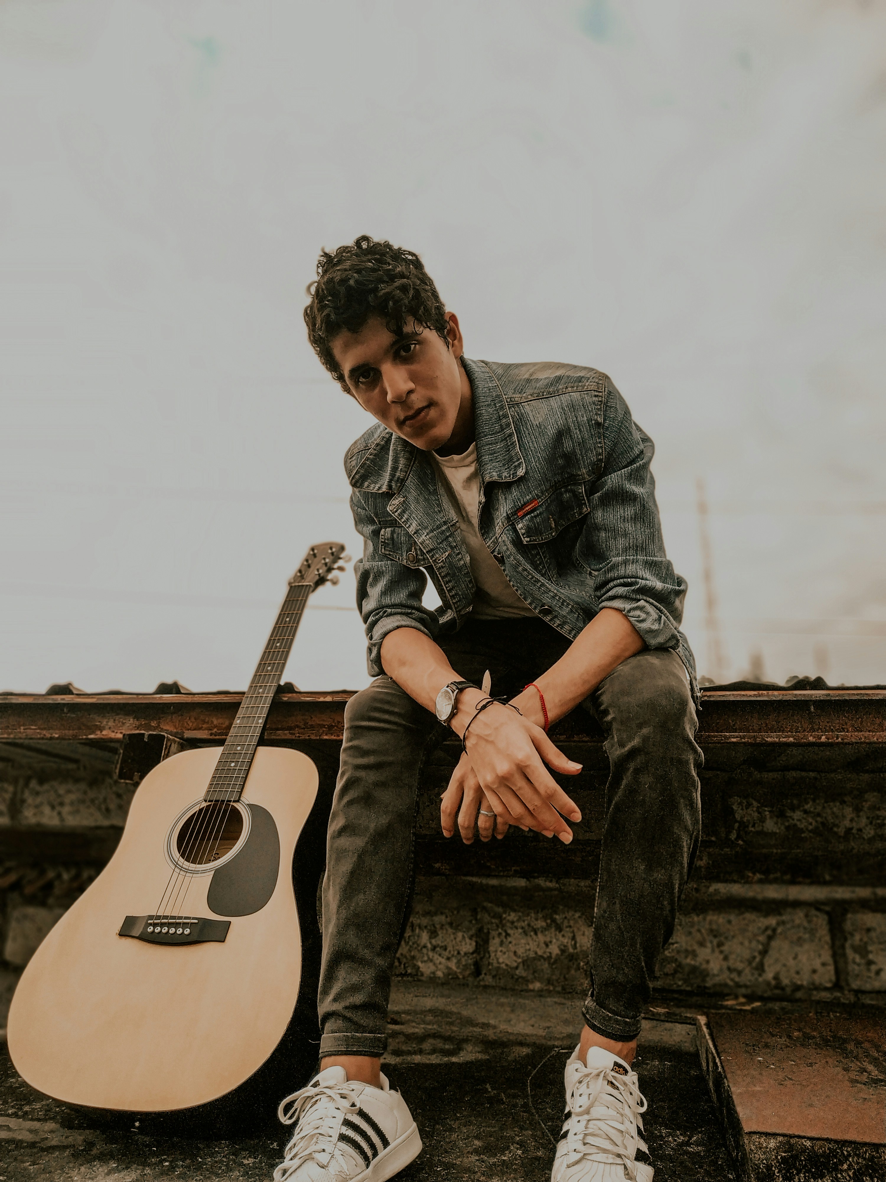 man in black and white plaid dress shirt playing acoustic guitar