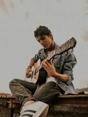A soulful musician playing acoustic guitar outdoors.