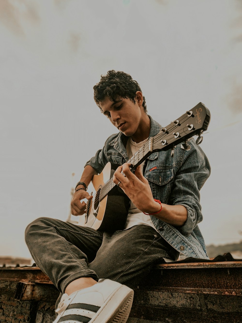 man in blue denim jacket playing guitar