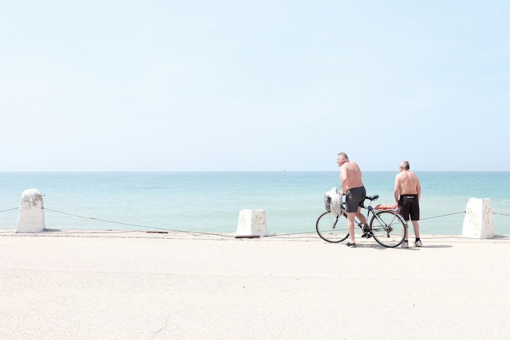 man and woman riding bicycle on beach during daytime