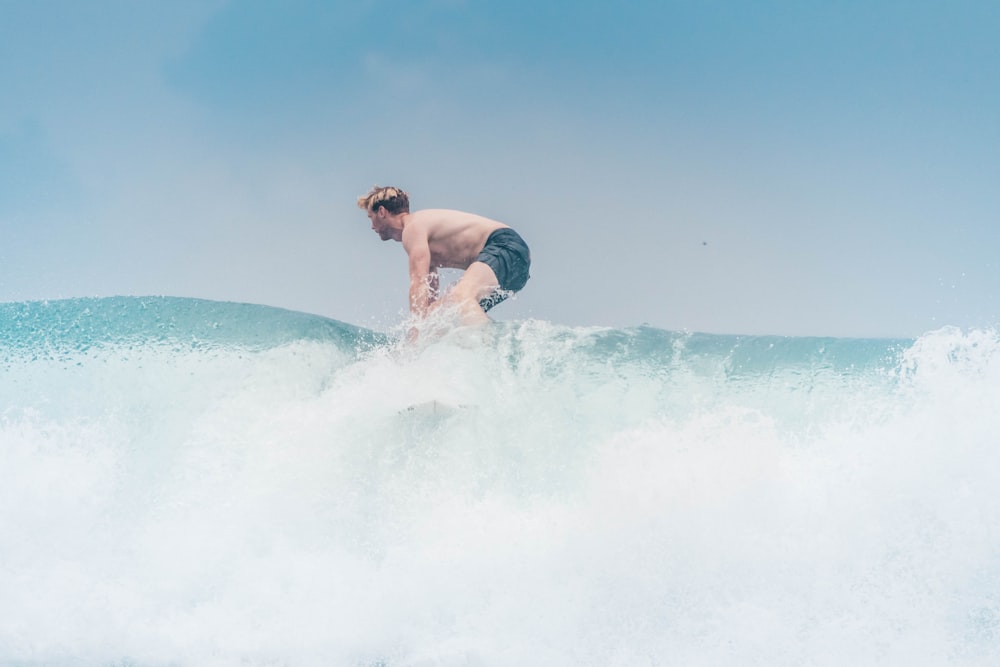 man in black shorts surfing on sea waves during daytime