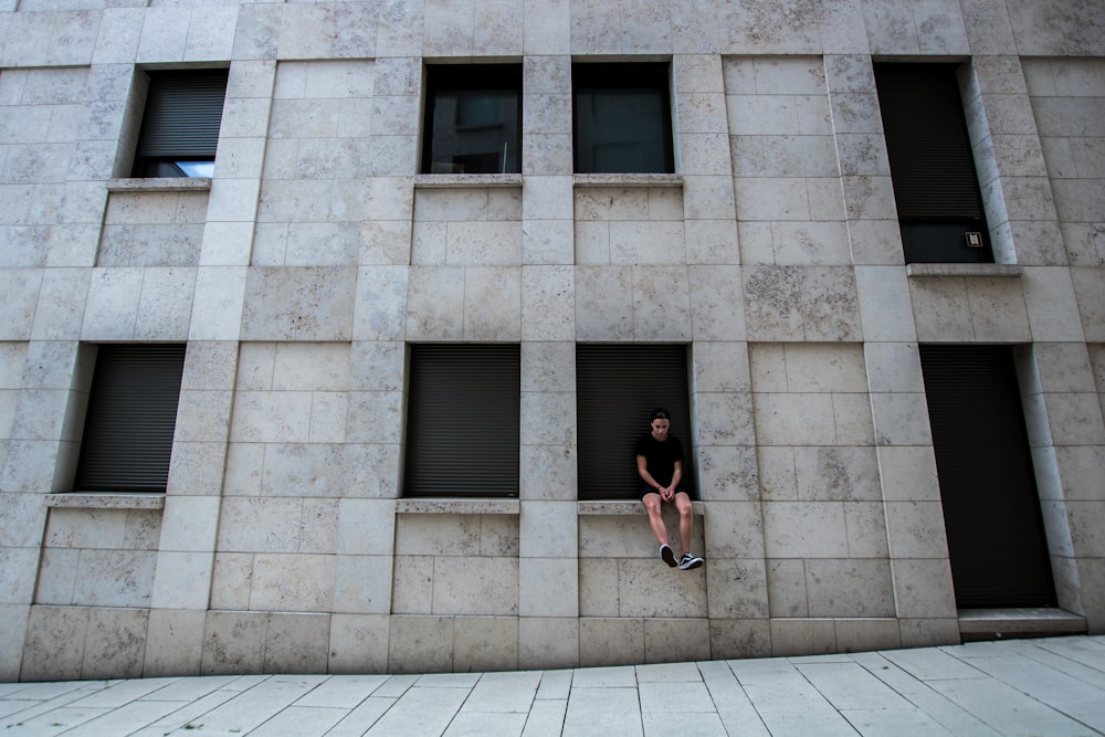 woman in black tank top and black shorts standing in front of gray concrete building during