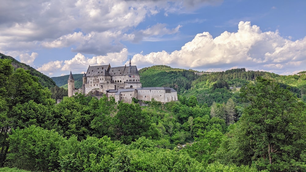 Weiße Betonburg umgeben von grünen Bäumen unter weißen Wolken und blauem Himmel tagsüber