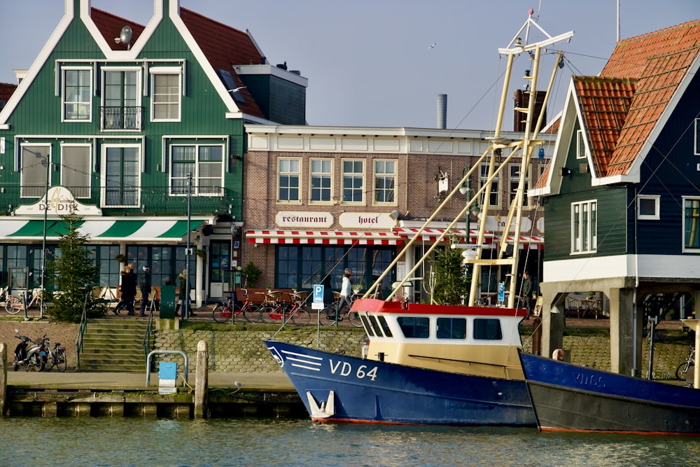 Barco azul y blanco en el agua cerca de un edificio de hormigón marrón durante el día