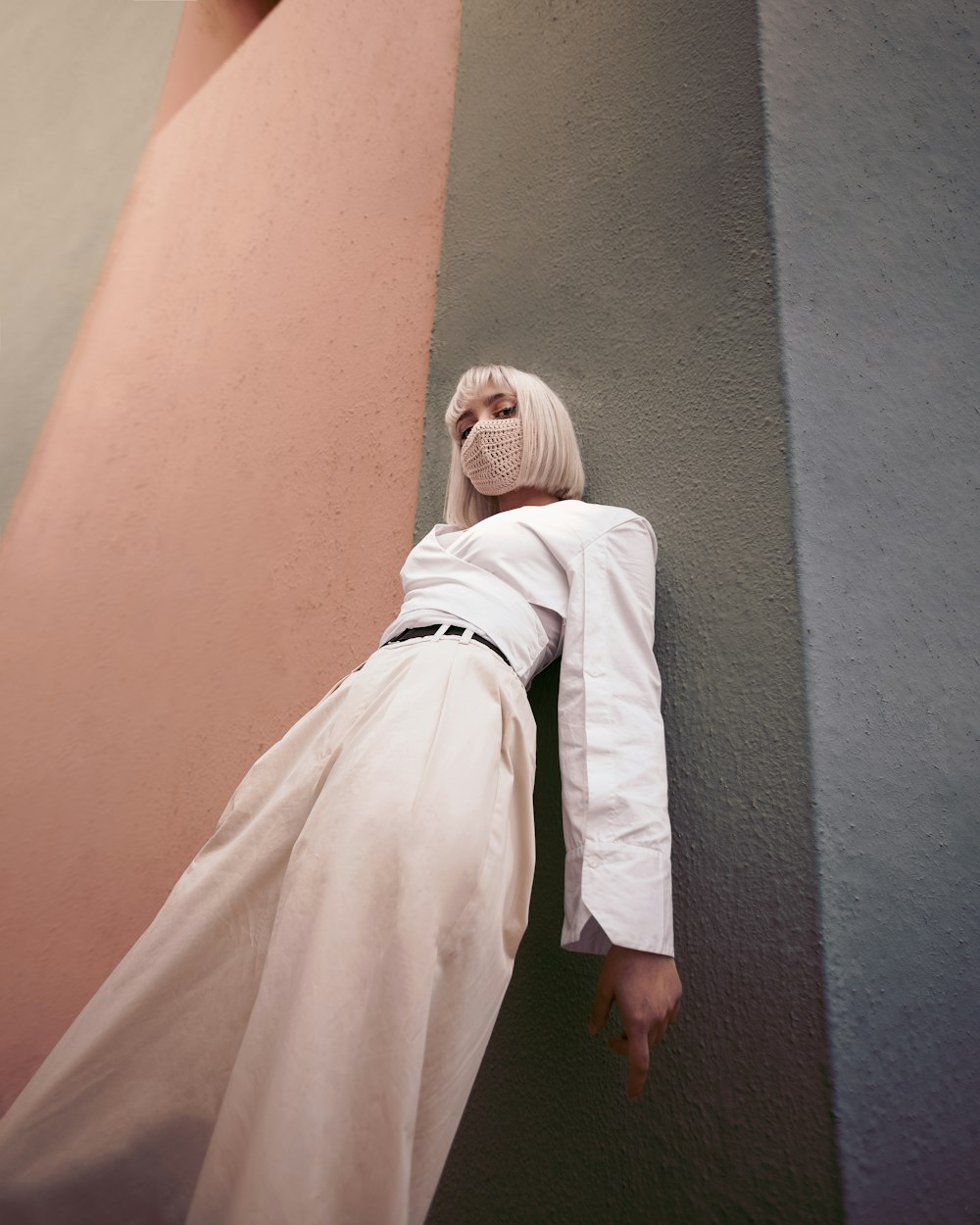 woman in white robe leaning on wall