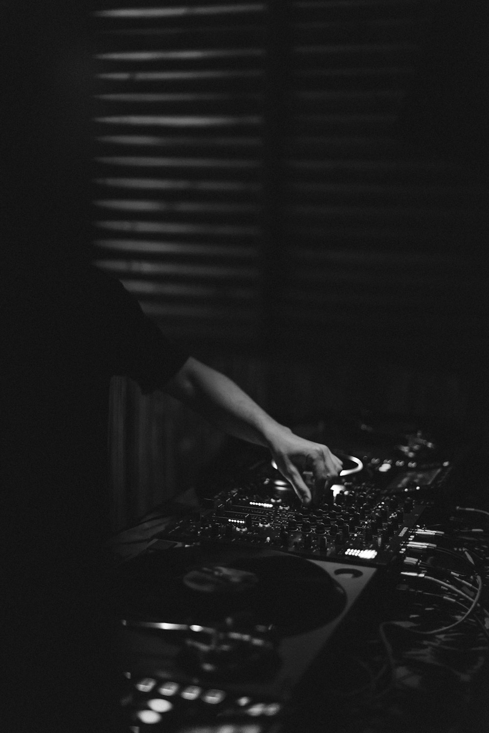 Foto en escala de grises de una persona tocando el controlador de DJ