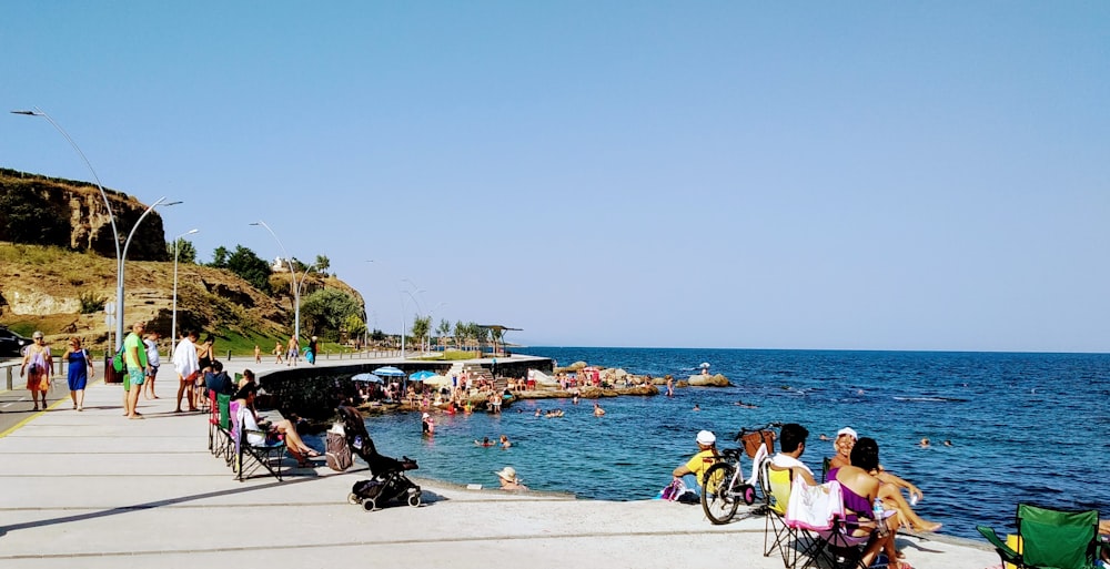 people riding bicycles on gray concrete pavement near body of water during daytime