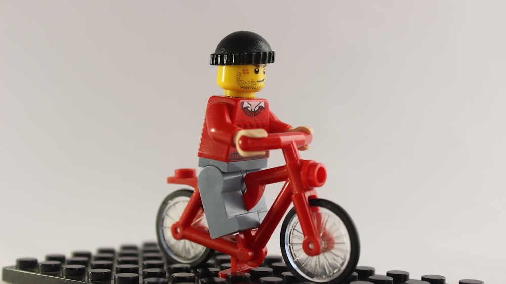lego minifig riding red and white bicycle