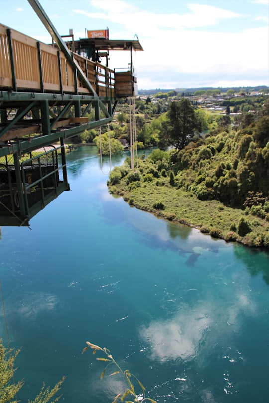brown wooden bridge over river during daytime in Lake Taupo New Zealand