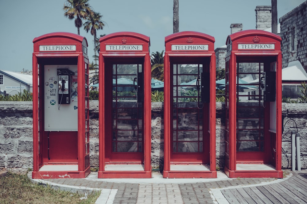 red telephone booth near green tree during daytime