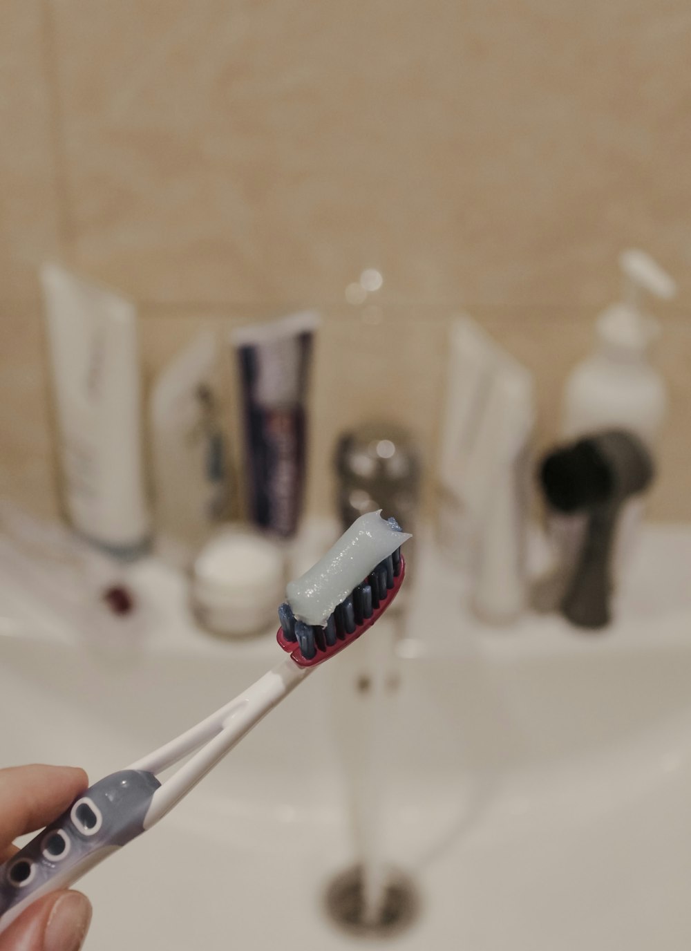 white and red toothbrush on white ceramic sink