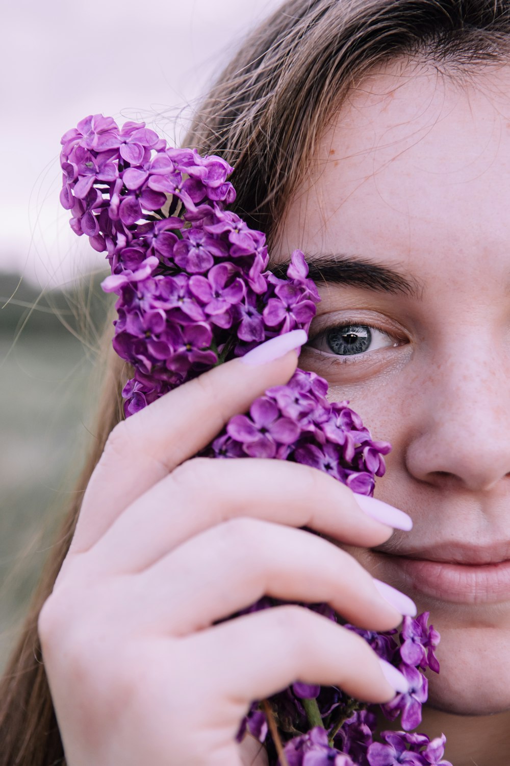 クローズアップ写真で紫色の花を保持している女性