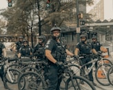 men in black and grey camouflage uniform riding on bicycle during daytime
