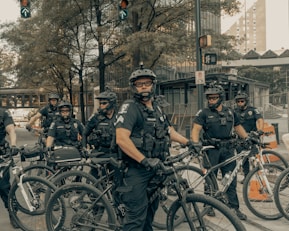 men in black and grey camouflage uniform riding on bicycle during daytime