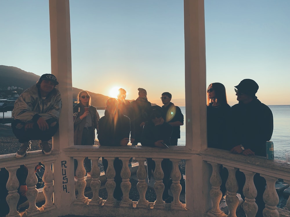 silhouette of people sitting on wooden fence during sunset