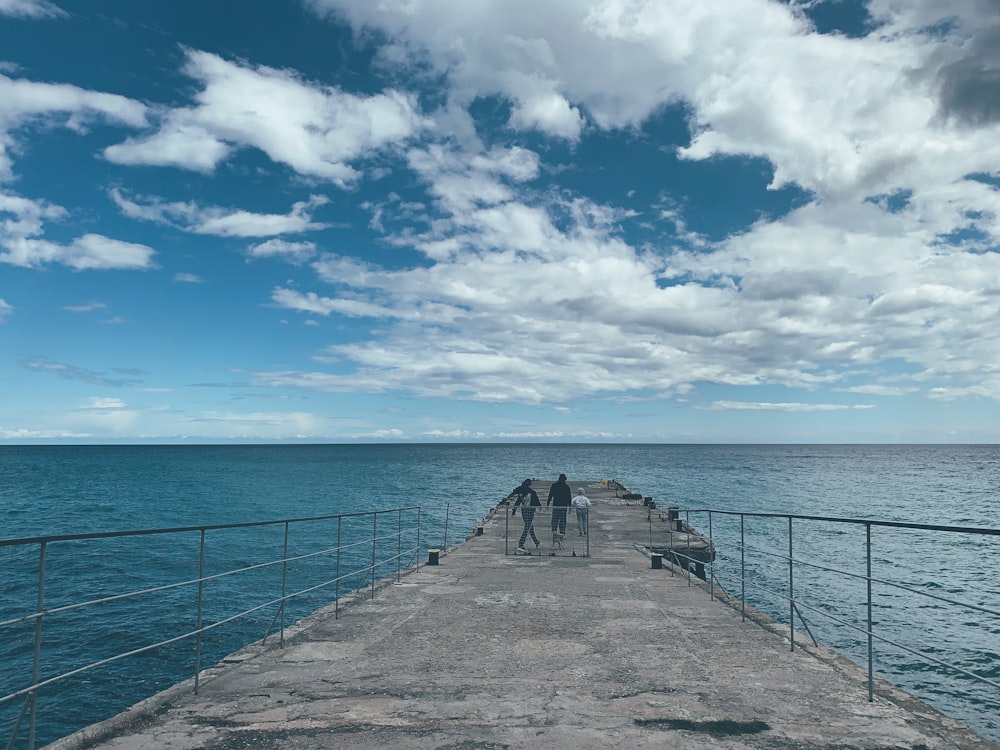 brown wooden dock on sea under blue sky and white clouds during daytime