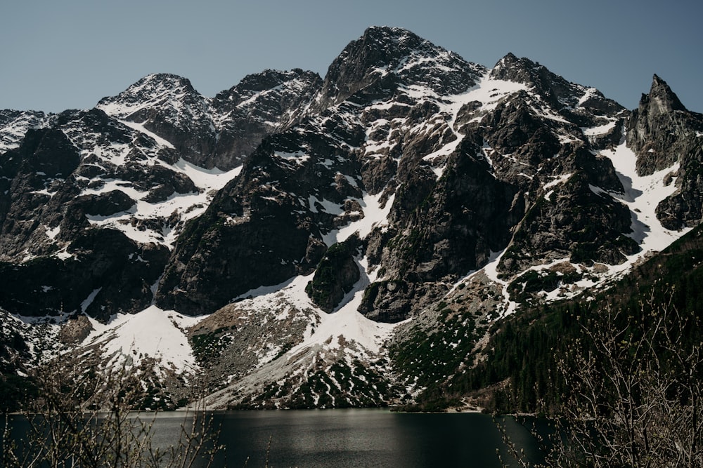 snow covered mountain near body of water during daytime